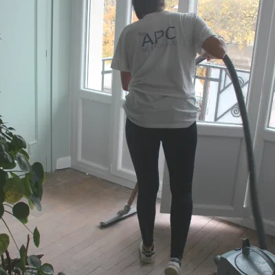 Une femme passe avec un tee-shirt «APC Nettoyage» passe l'aspirateur.